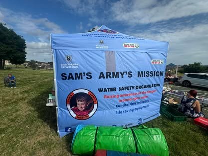 Two people holding Sam's Army t-shirts inside a car dealership.