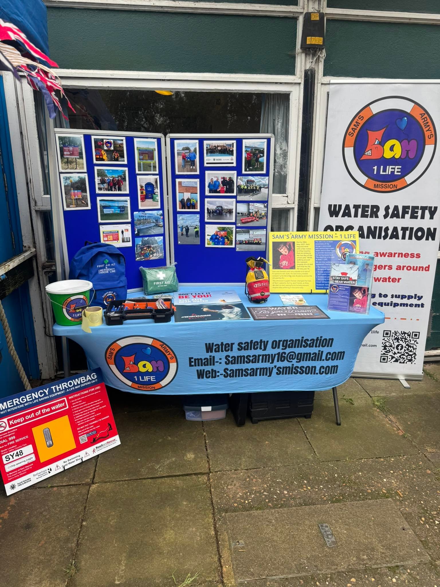 The Sam's Army stall: a blue boat-shaped table with leaflets, a throwbag and a banner reading Water Safety Organisation.